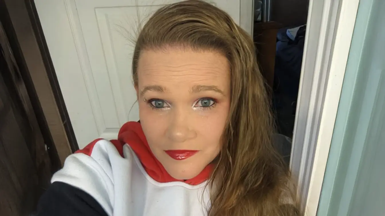 Portrait of Audrey Hess in 2024, looking directly at the camera in a white, red, and black hoodie.